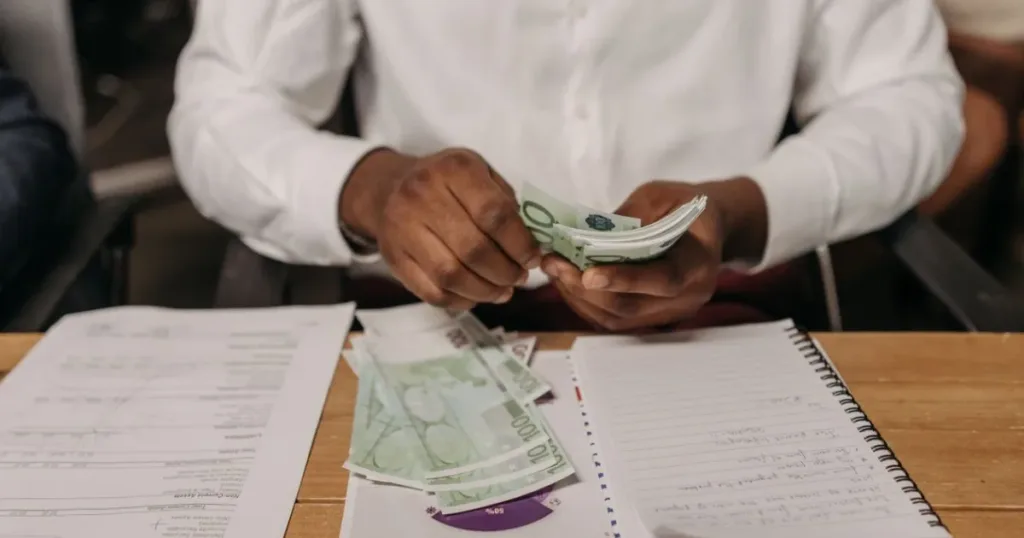 Business owner counting cash and recording it in a notebook