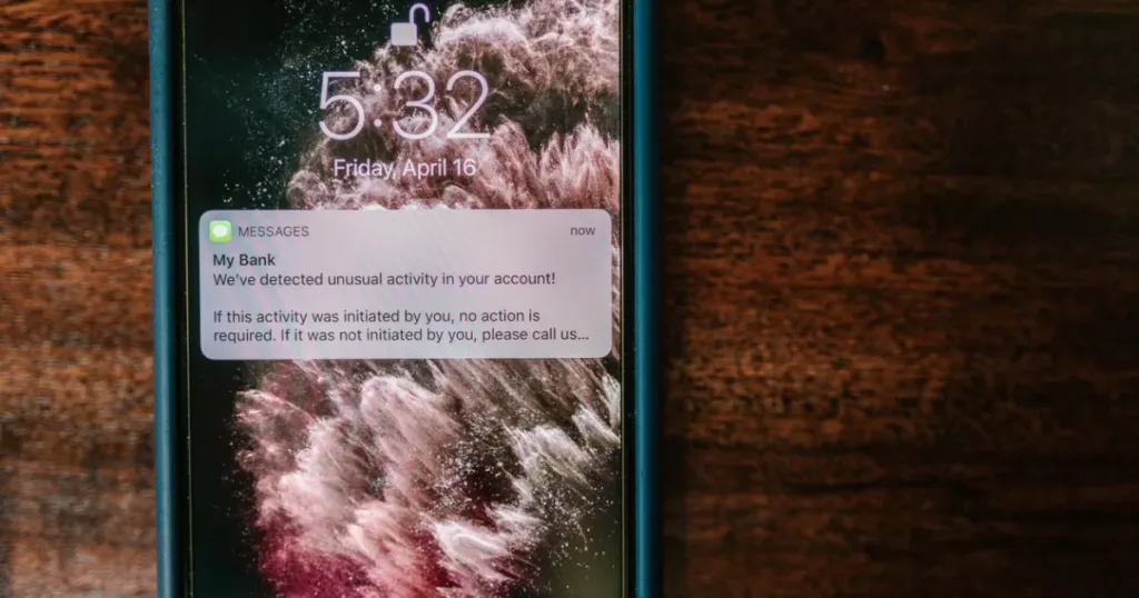Smartphone displaying a bank alert notification on a wooden table