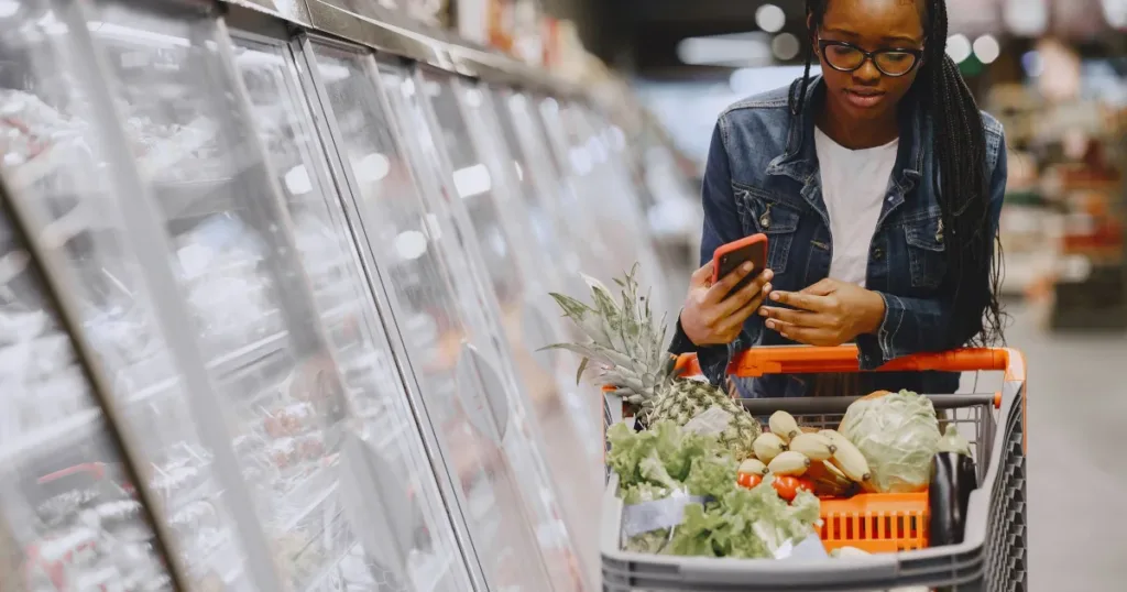 Woman grocery shopping while checking her phone