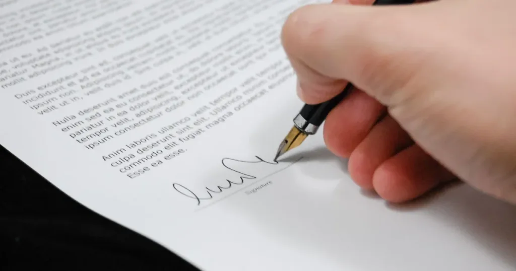 Person signing a document at a desk