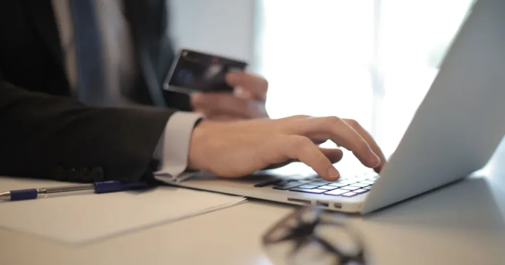 Person typing on a laptop while reviewing a credit card application