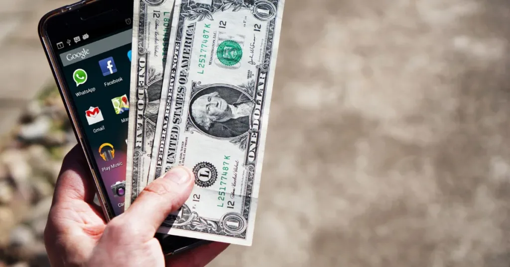 Smartphone banking app next to cash representing a bank card comparison