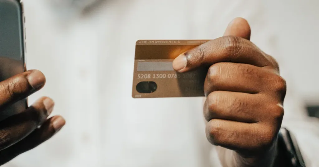 Hand holding a bank card while using a phone