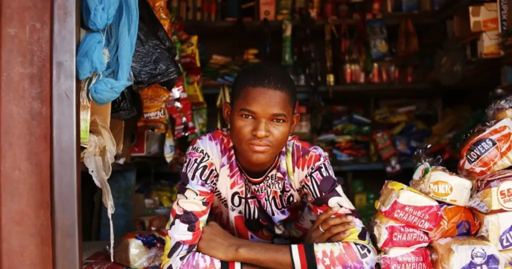Spaza shop owner standing at the counter of a small informal store in South Africa