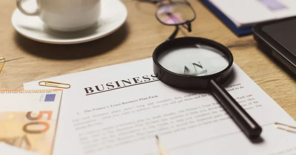 Person reviewing a financial document with a magnifying glass