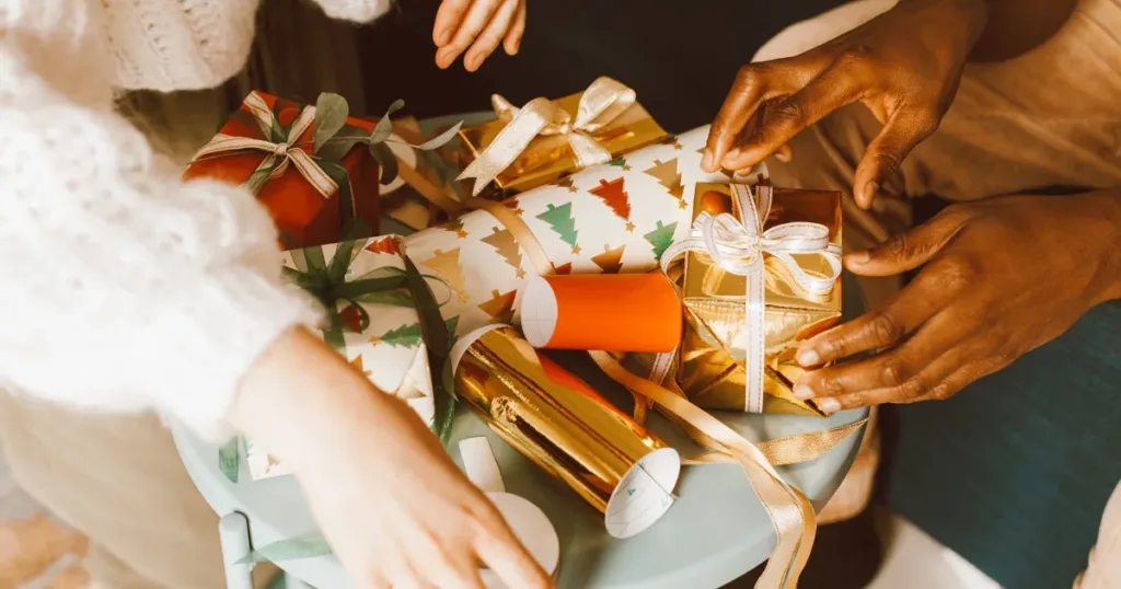 Hands preparing and wrapping Christmas gifts with colorful ribbon