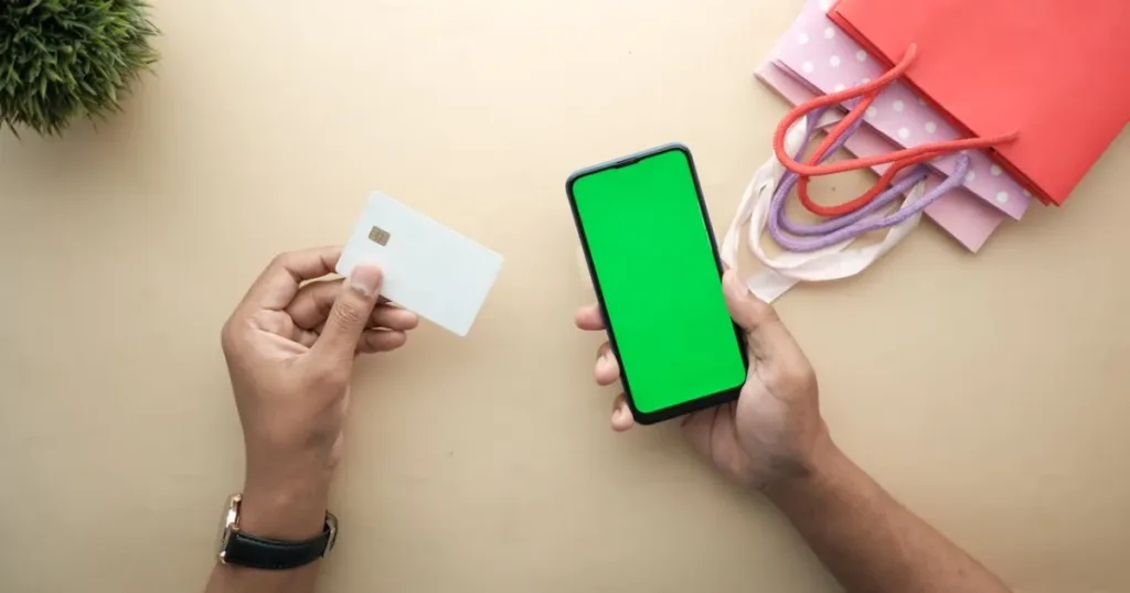 Hands holding a credit card next to a smartphone