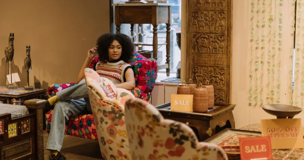 Woman relaxing on a chair in a furniture store, browsing sofas with sale signage visible