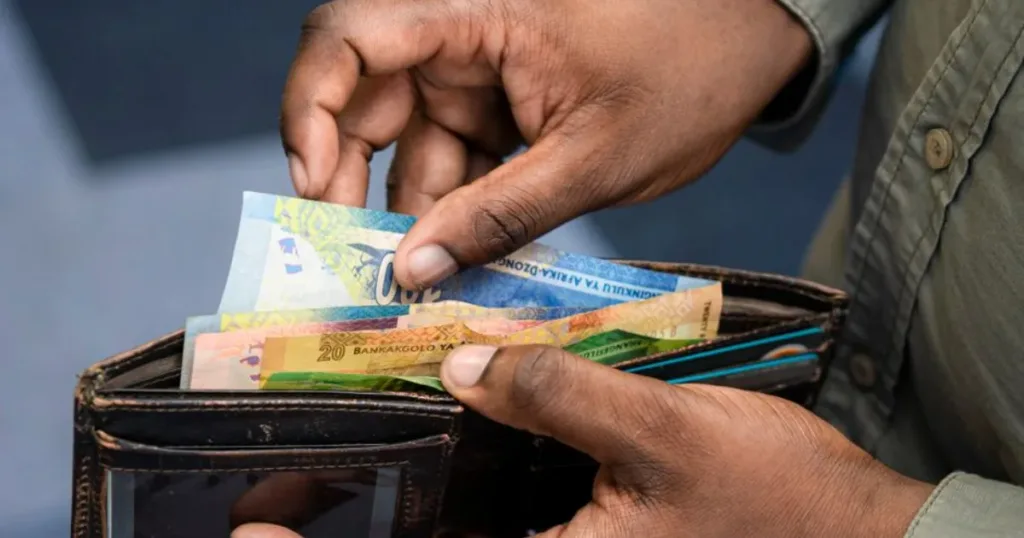 Person counting South African Rand cash notes