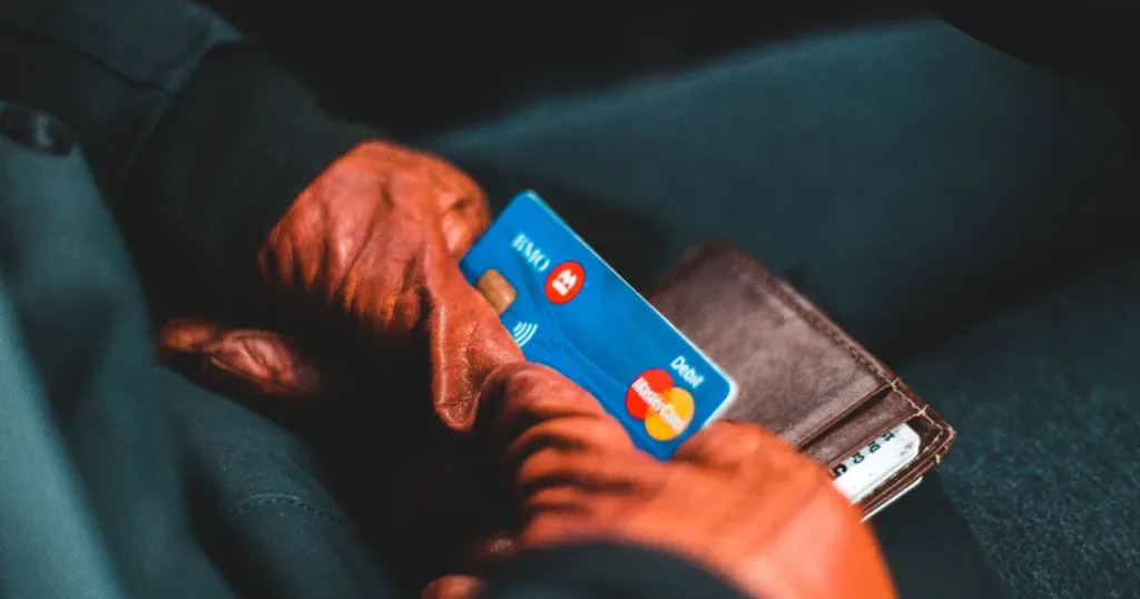 Hand holding a debit card next to a wallet