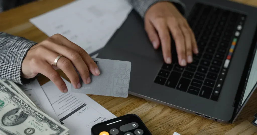 Person using a calculator with a credit card nearby