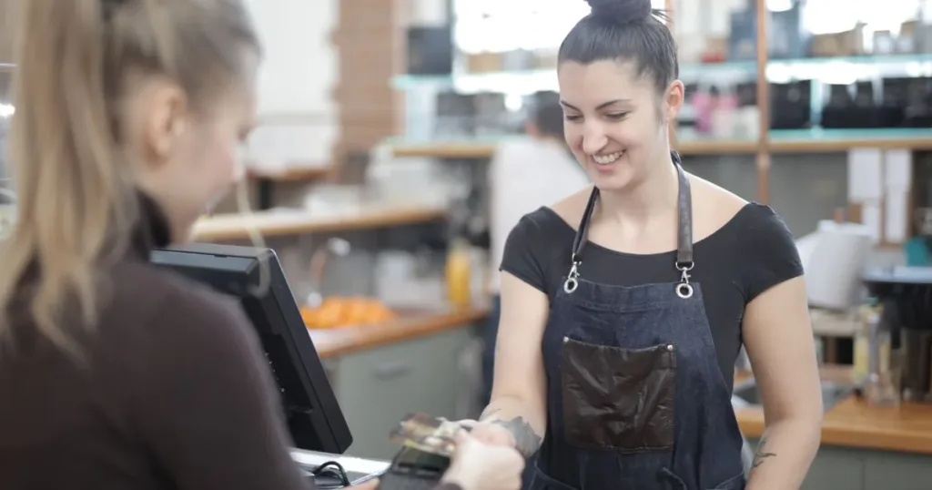 Smiling cashier helping a customer pay at a store counter