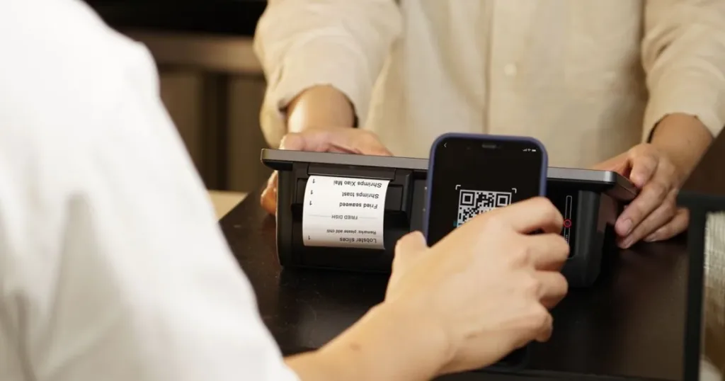 Person scanning a QR code to pay with a phone