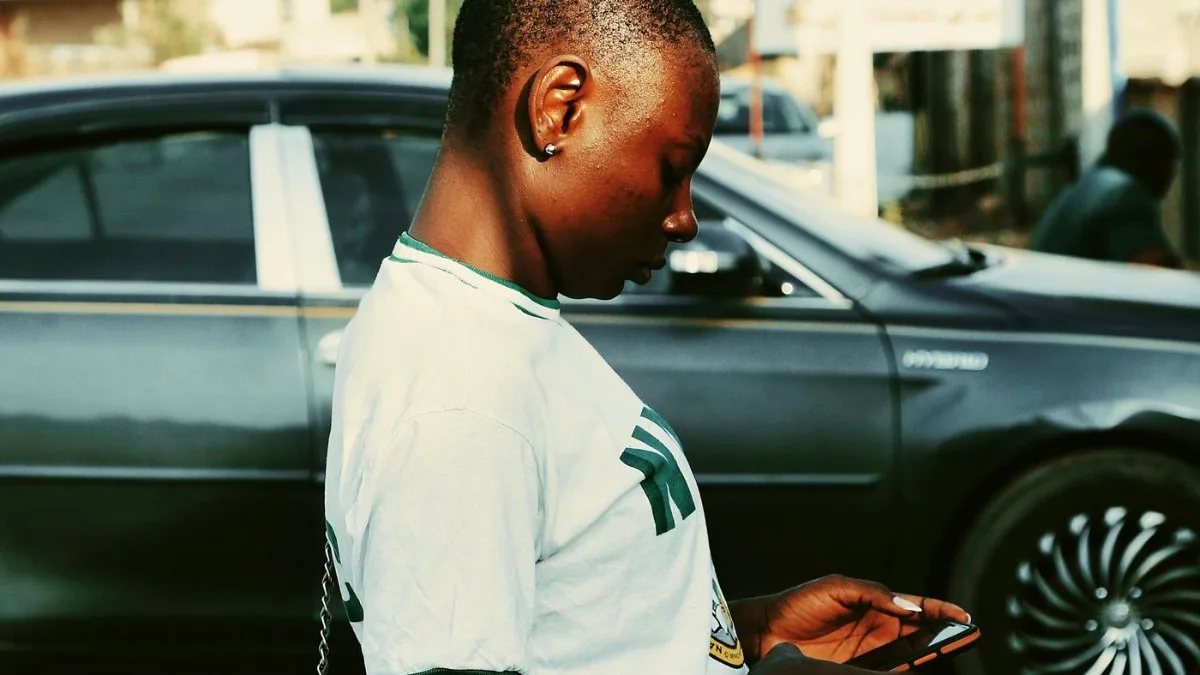 Young Nigerian woman checking her phone on a street in Nigeria